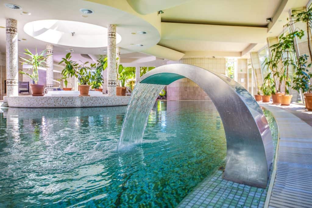 A large indoor pool with a fountain in it